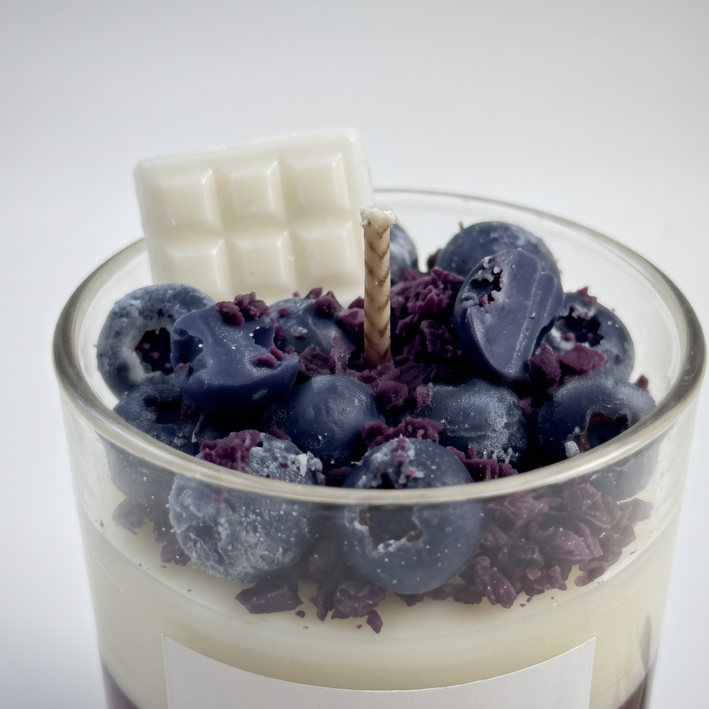 Macro close-up of SORA SCENT's Blueberry White Chocolate Parfait Candle, highlighting the realistic frosted texture of the wax blueberries, purple crumbs, and white chocolate bar topper.