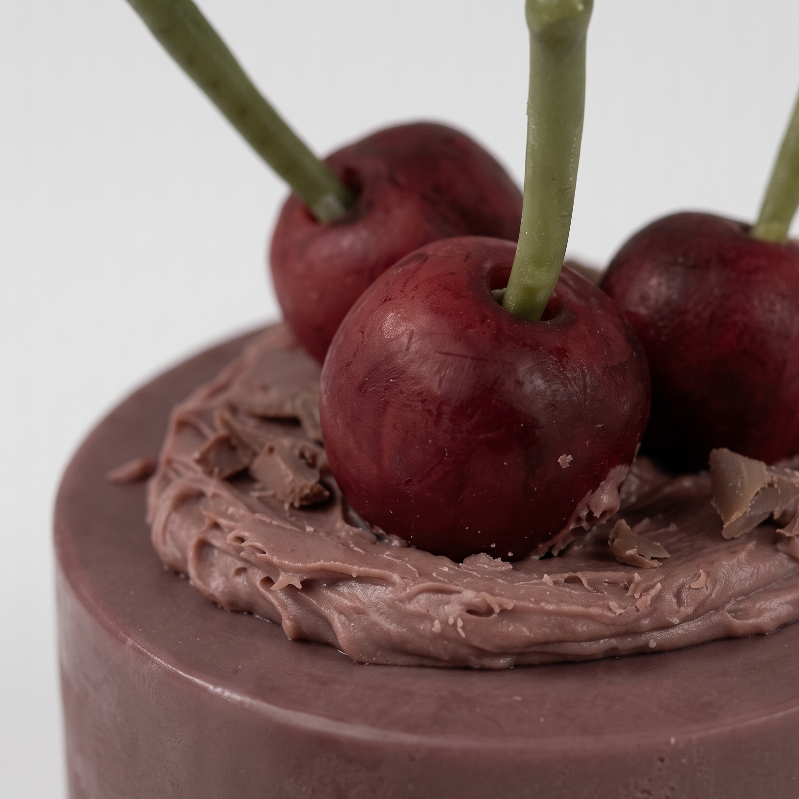 Macro close-up of SORA SCENT's Mini Chocolate Cherry Cake Candle, highlighting the glossy texture of the wax cherries, delicate stems, and realistic chocolate shavings on the ganache top.
