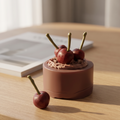 SORA SCENT Mini Chocolate Cherry Cake Candle styled on a dark wood coffee table next to a vintage ceramic mug and art books, creating a cozy autumn bakery ambiance.