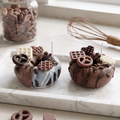 A lit Mini Chocolate Glazed Donut Candle by SORA SCENT burning softly, featuring a warm flickering flame illuminating the rich cocoa wax toppings and donut base.