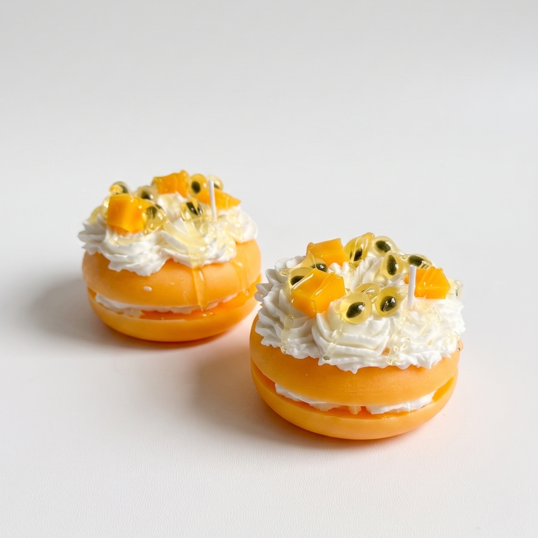 SORA SCENT Mini Passion Fruit and Mango Macaron Candle on a clean background, showcasing its pastel yellow biscuit base, whipped cream frosting, mango cubes, and passion fruit seeds with dripping glaze.