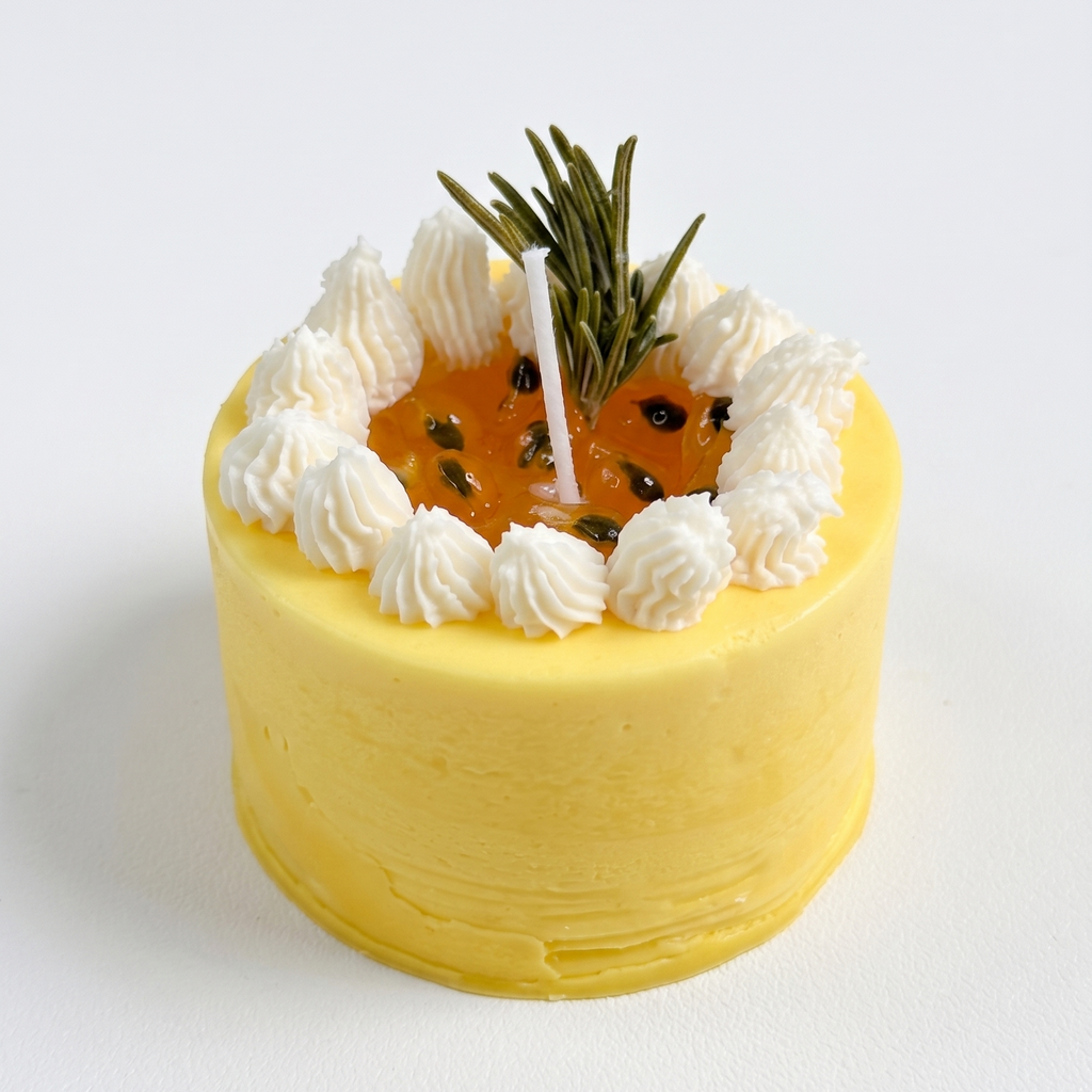 Handcrafted Mini Passion Fruit Mousse Cake Candle by SORA SCENT on a clean background, featuring yellow frosted soy wax, piped white cream, and an amber gel wax center with seeds.