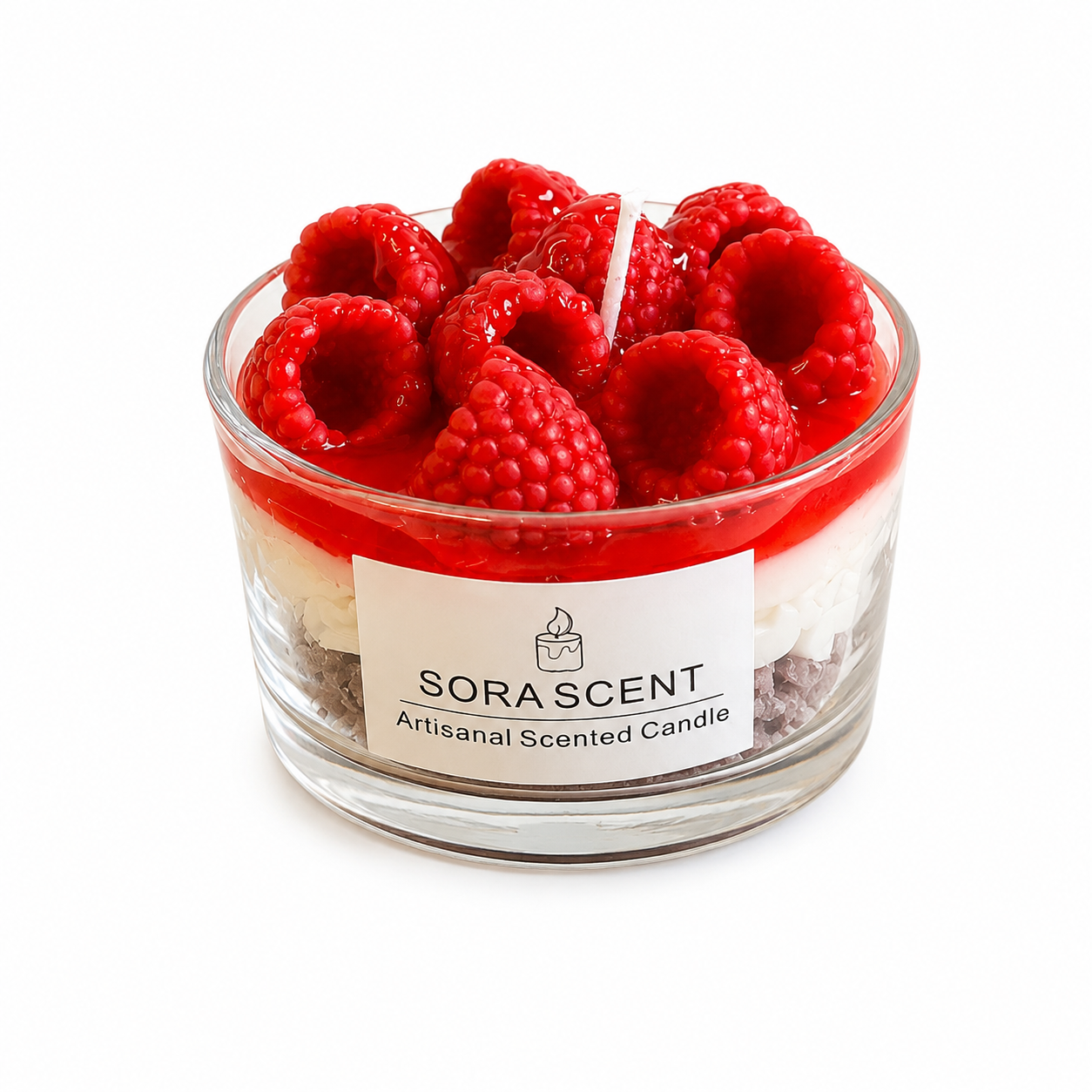 showcases a lit handcrafted Raspberry Mousse Tart Candle by SORA SCENT on a white wooden nightstand in a cozy, softly blurred bedroom setting, featuring distinct cookie crumb and cream layers topped with glowing red wax raspberries, with loose decorative wax berries resting beside it.