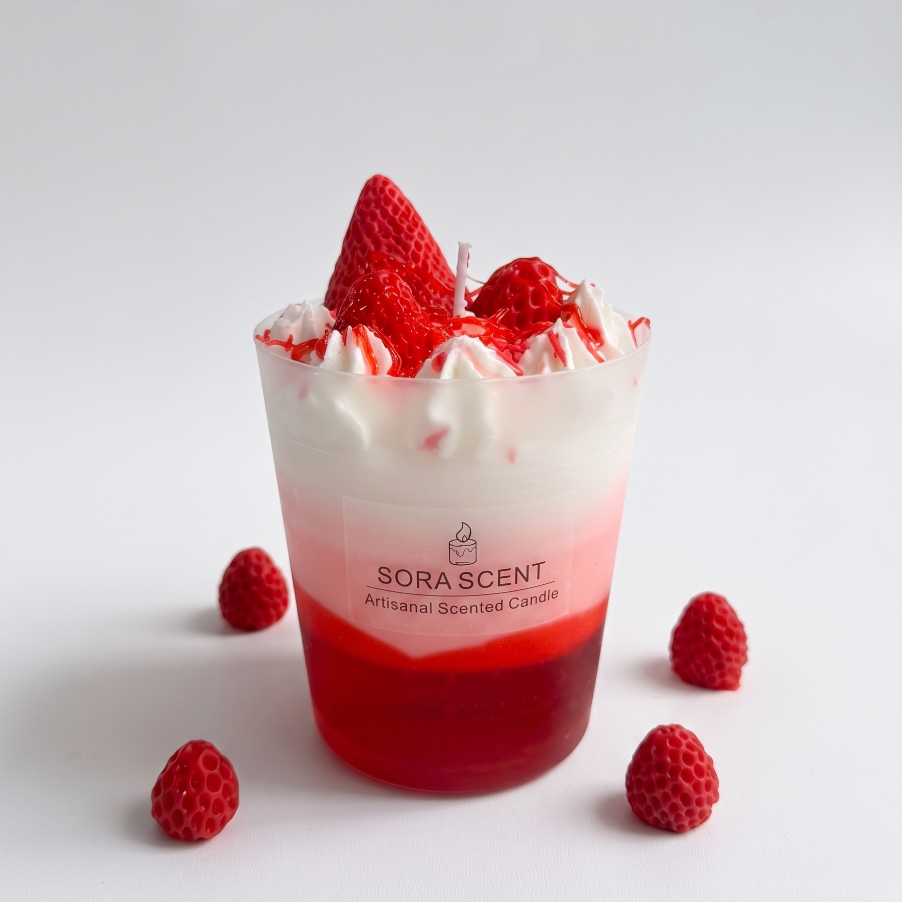 A 8.5x8.5x11cm handcrafted Strawberry Raspberry Panna Cotta Sundae Candle by SORA SCENT in a frosted cylindrical glass vessel on a pure white studio background, featuring deep red gel wax jelly, pink-to-white ombre soy wax, whipped cream wax, and realistic red berries.