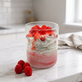 showcases a handcrafted Strawberries & Cream Sundae Candle by SORA SCENT in a clear glass jar, featuring a layered pink-and-white base, realistic white whipped cream wax, glossy strawberry syrup drizzle, and realistic red berries on top, displayed next to decorative wax berries on a marble surface.