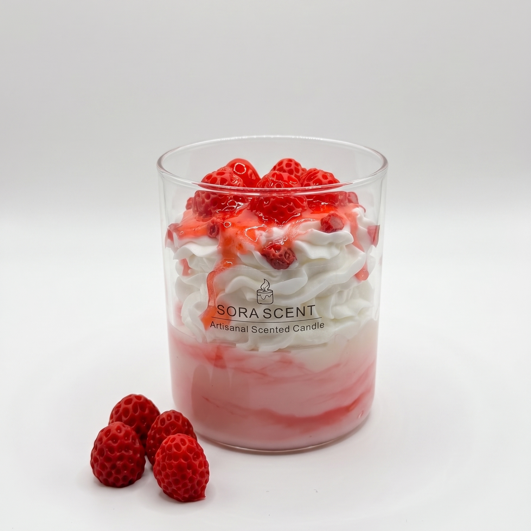 showcases a handcrafted Strawberries & Cream Sundae Candle by SORA SCENT in a clear glass jar, featuring a layered pink-and-white base, realistic white whipped cream wax, glossy strawberry syrup drizzle, and realistic red berries on top, displayed next to decorative wax berries on a marble surface.