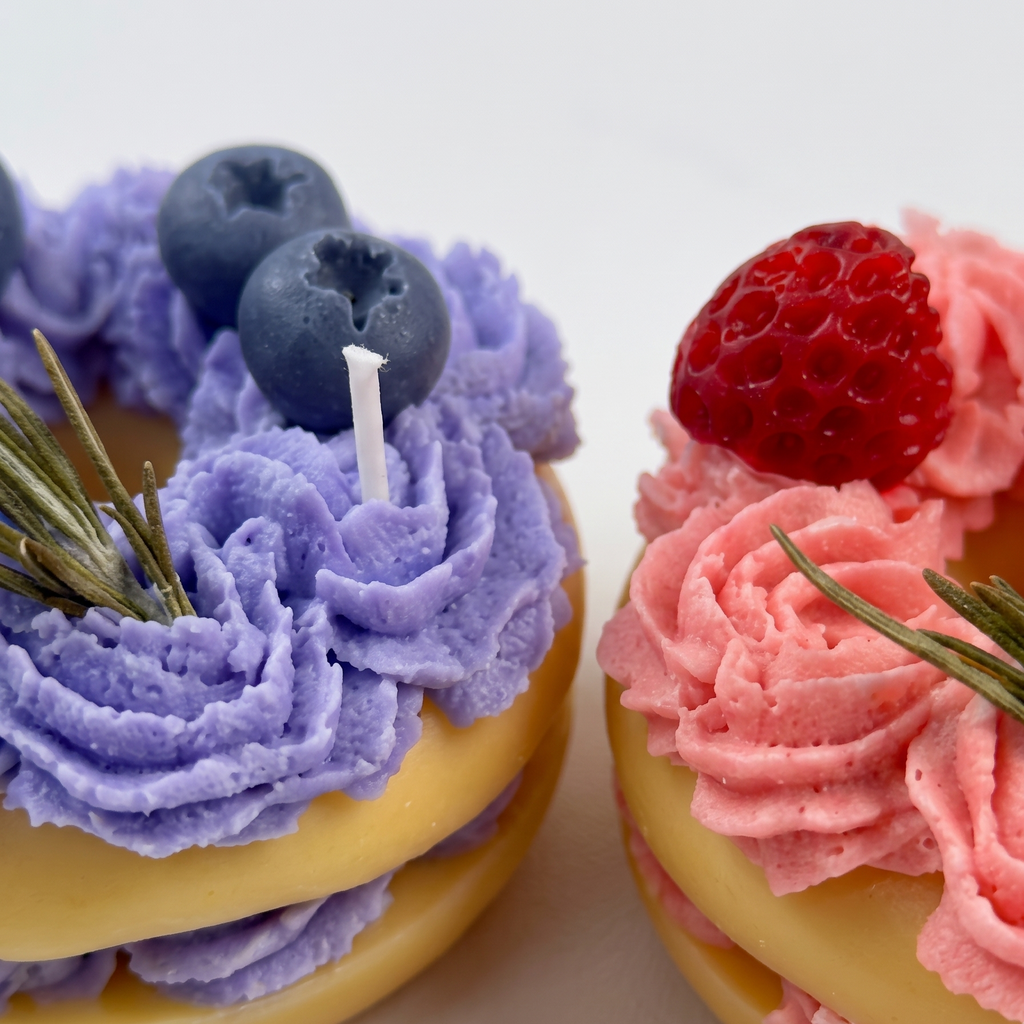 sora-scent-mini-macaron-candle-macro-details.jpg` | Macro close-up of SORA SCENT's Mini Berry Macaron Candle, highlighting the delicate swirl texture of hand-piped soy cream frosting and detailed seed textures on the wax fruit toppers. 