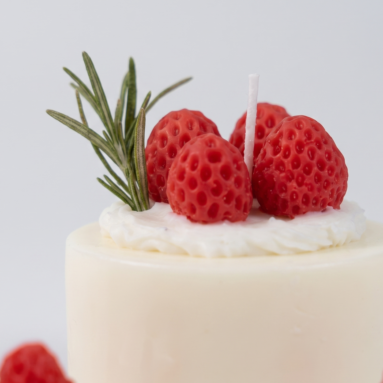 Macro close-up of SORA SCENT's Mini Strawberry Mousse Cake Candle, highlighting the detailed seed texture of the red wax strawberries and delicate white cream frosting.