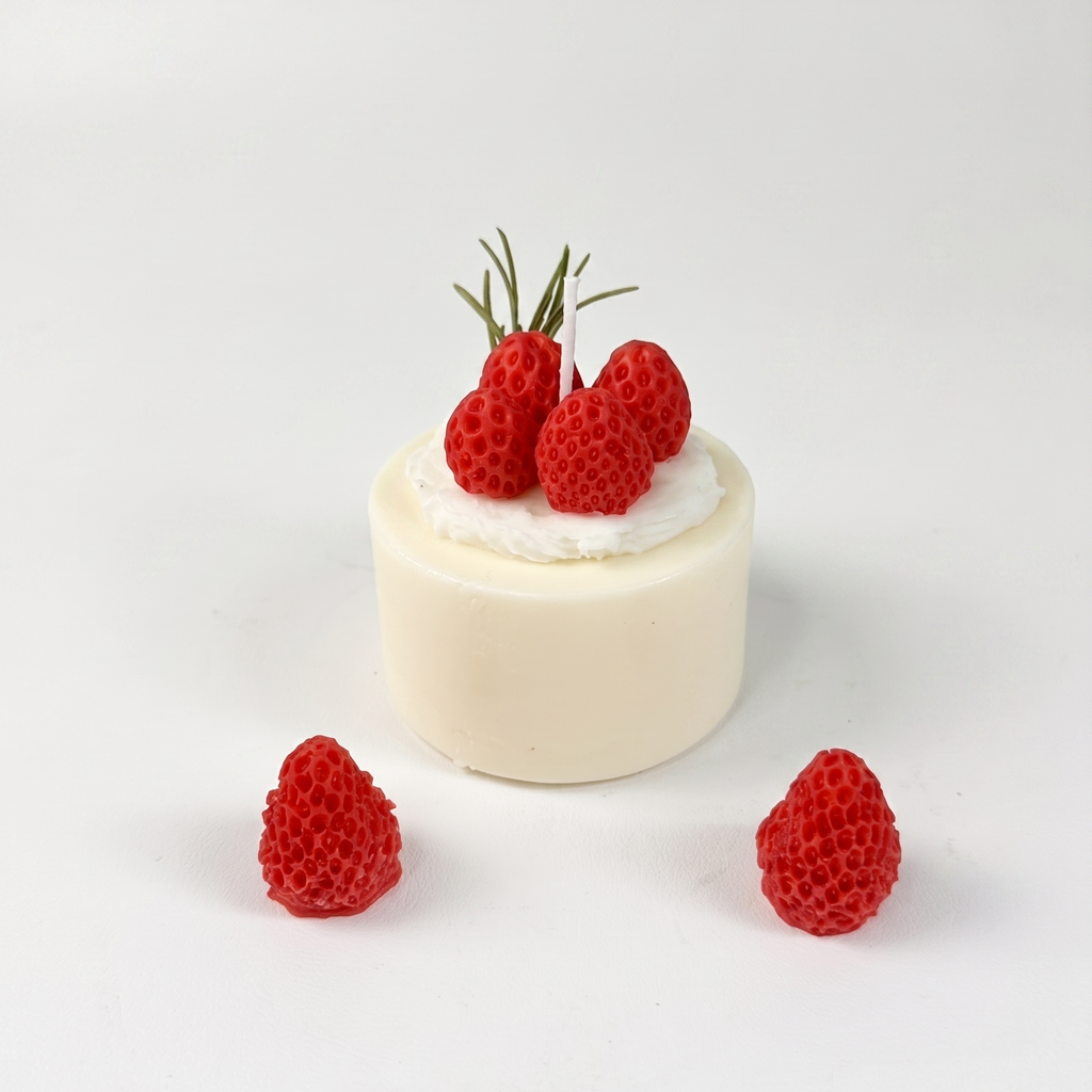 SORA SCENT Mini Strawberry Mousse Cake Candle on a clean background, showcasing its smooth white cylinder base, whipped cream frosting, detailed red wax strawberries, and green rosemary garnish.